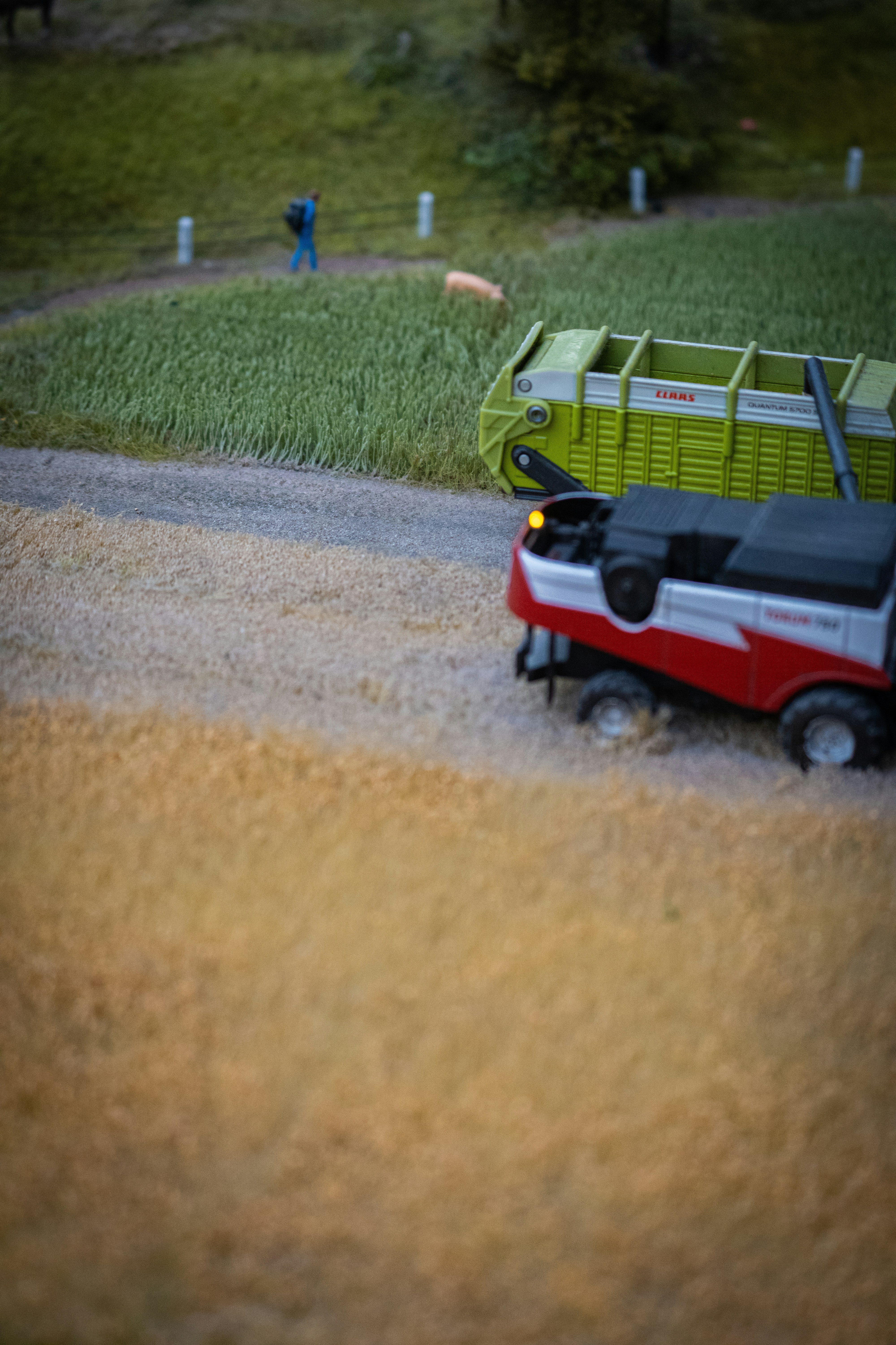 a toy car driving down a road next to a green trailer
