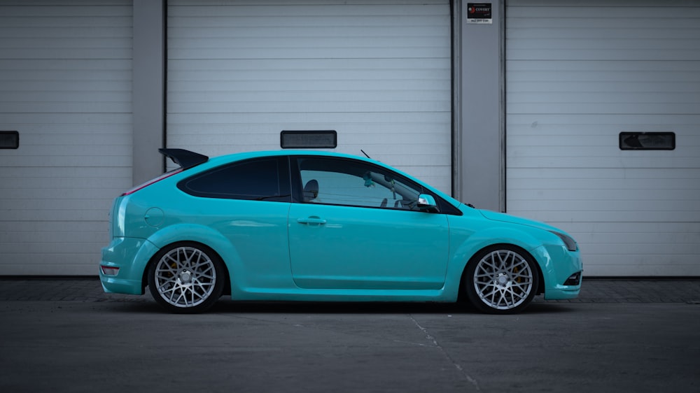 a blue car parked in front of two garage doors