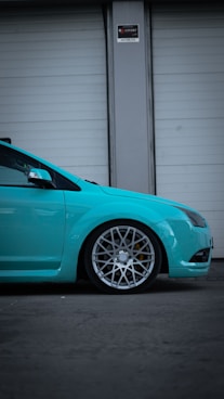 a blue car parked in front of a garage