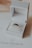 A luxurious ring with dark gemstones is elegantly presented in an open white jewelry box. The box rests on a card with branding and a diamond logo. The background is softly out of focus, enhancing the focus on the ring.