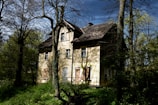 An old abandoned house with strange shadows visible in the windows at night.