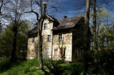 An old abandoned house with strange shadows visible in the windows at night.