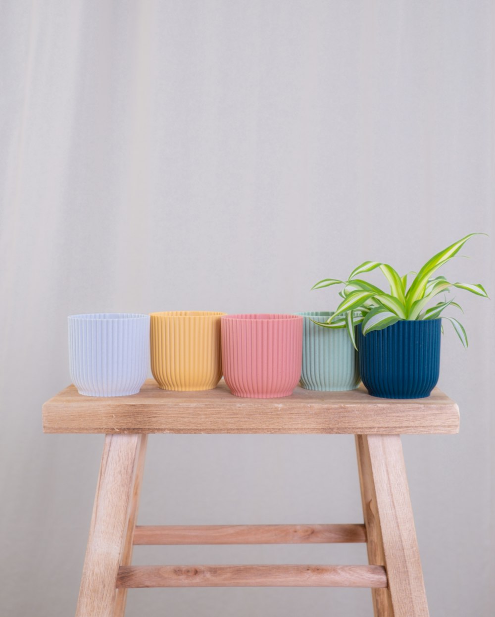 a wooden table topped with three different colored cups