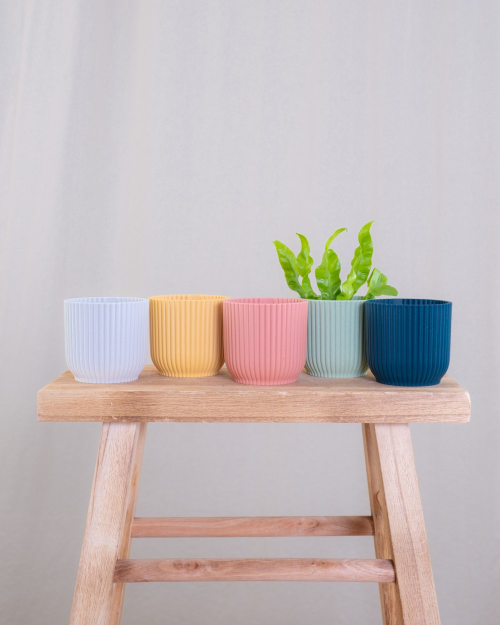 Una mesa de madera cubierta con tres tazas de diferentes colores