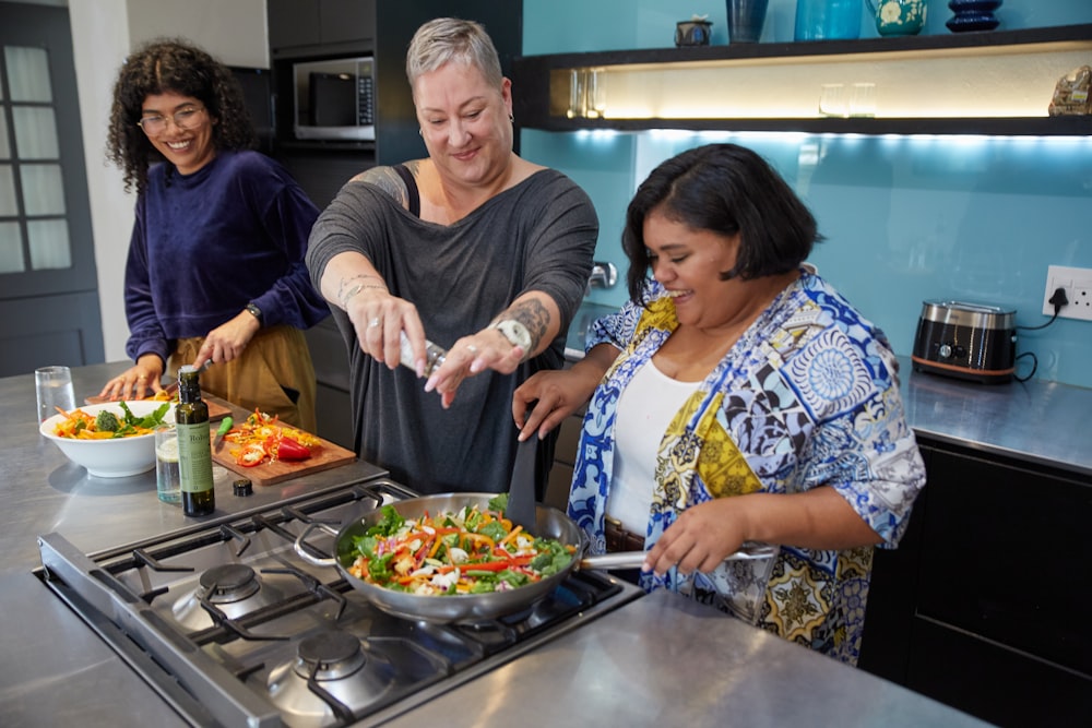 Un hombre y dos mujeres preparando comida en una cocina