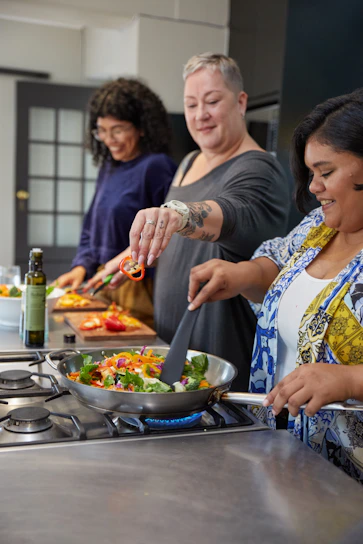 A happy person cooking a healthy meal in a cozy kitchen setting.