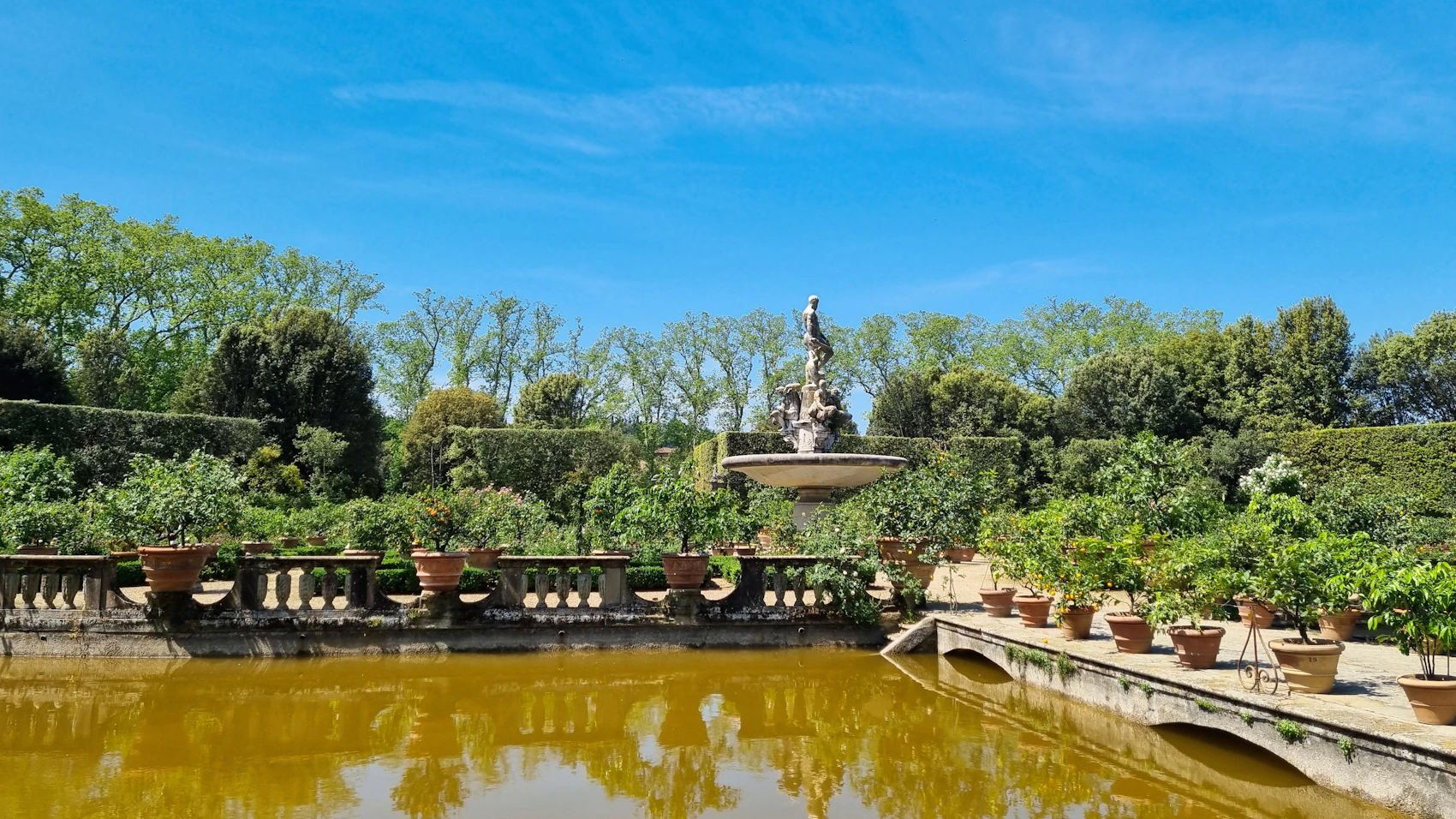 A fountain surrounded by greenery and terracotta pots in Florence's Boboli Gardens