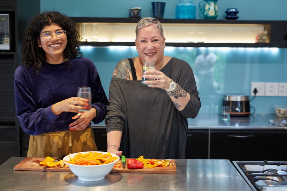 a couple of women standing next to each other in a kitchen