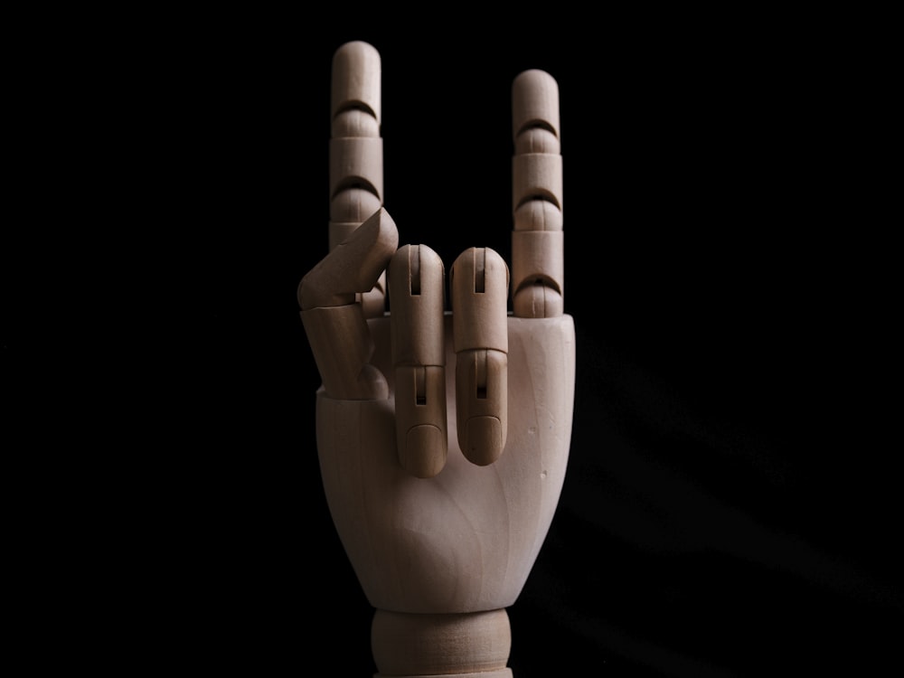 Una escultura de madera de una mano haciendo un signo de paz
