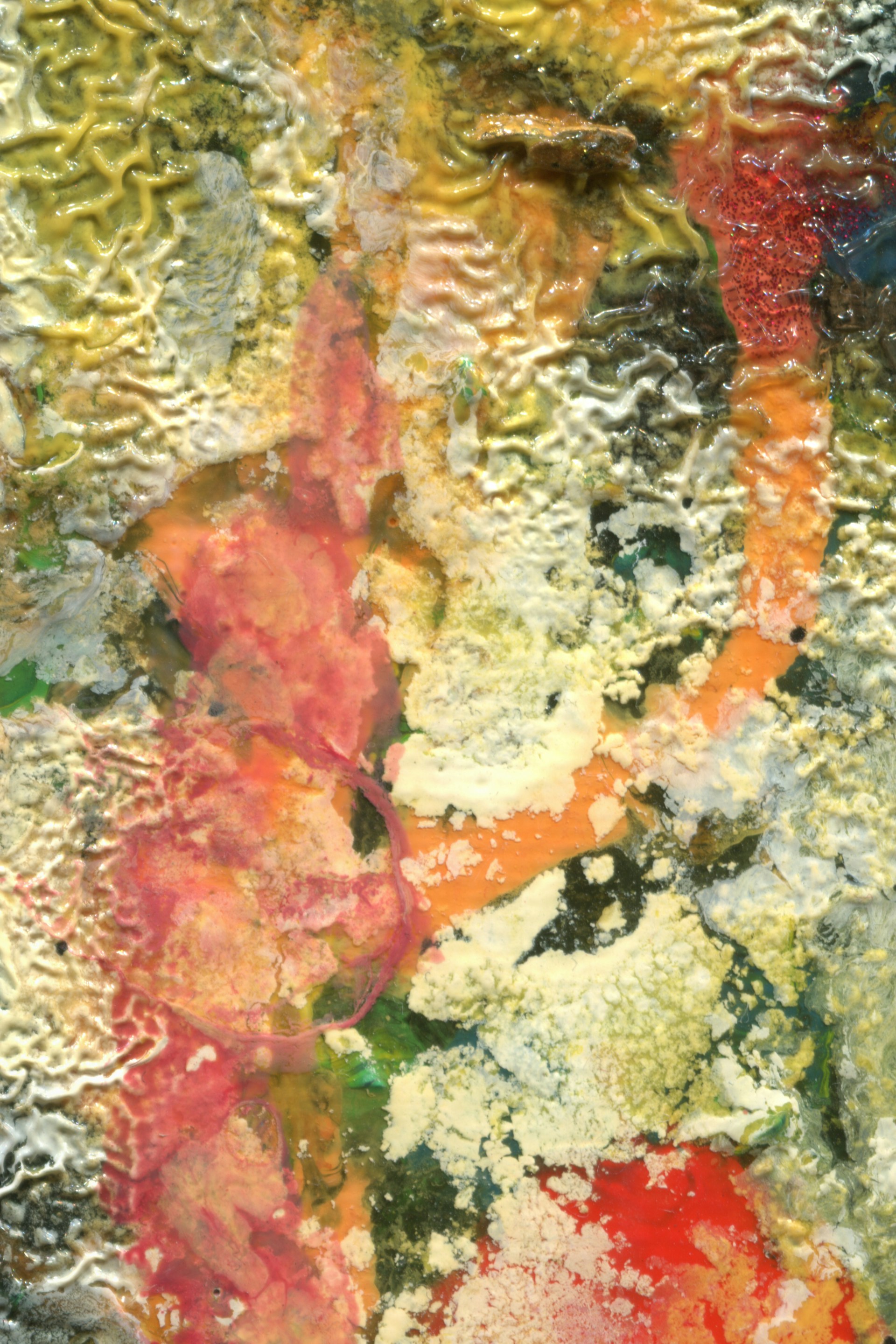 A textured abstract artwork featuring a vibrant mix of colors, including splashes of red, yellow, and green. The composition has a rough, almost organic appearance with visible brushstrokes and a swirling, layered effect.