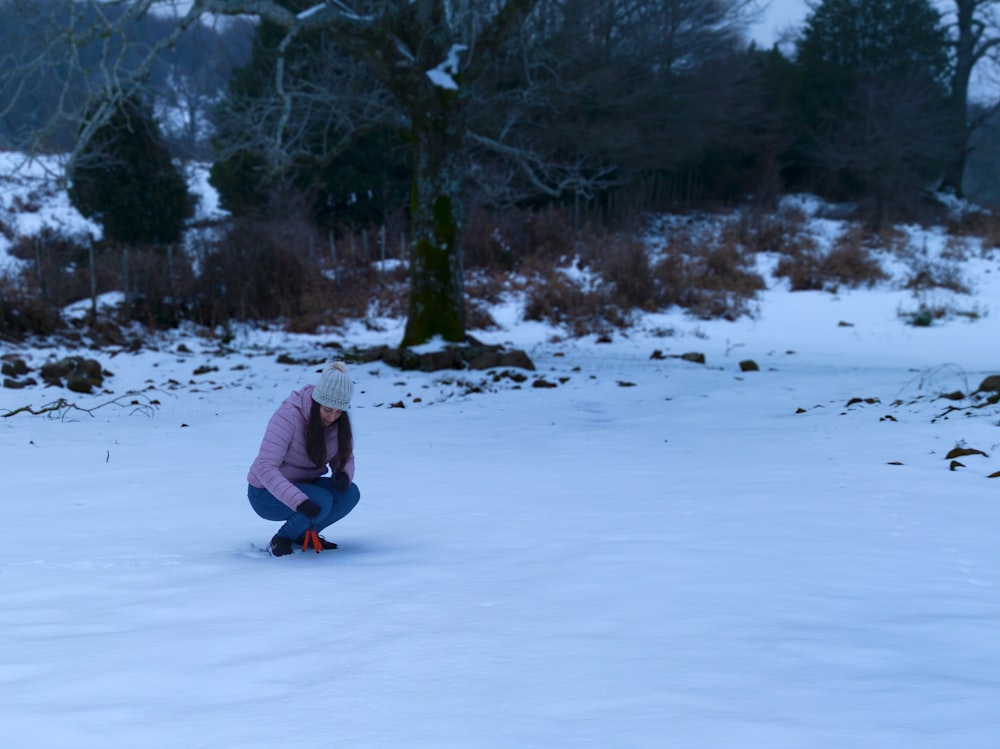 a person kneeling down on a snow covered field