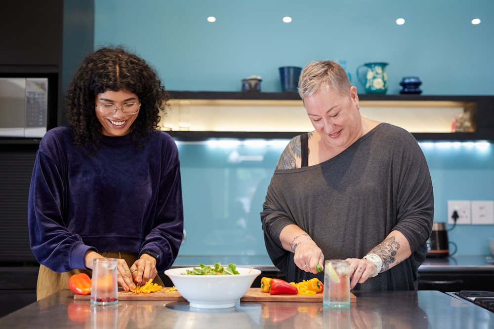 a couple of women standing in a kitchen preparing food