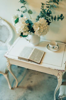 a table with a book and a vase with flowers on it