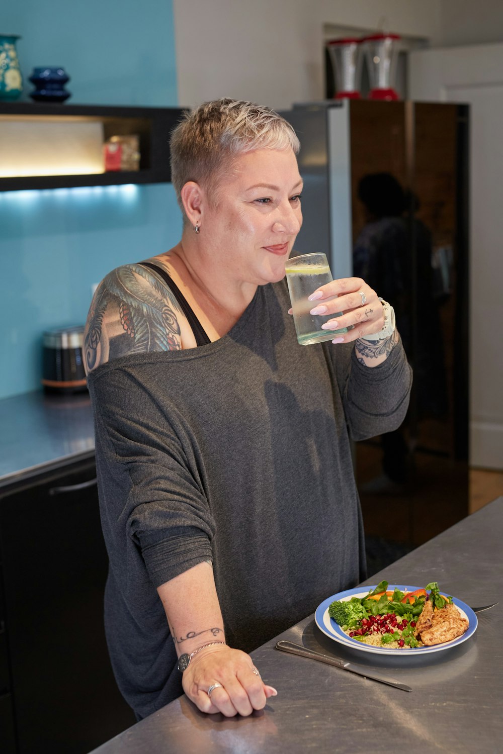 a woman sitting at a table drinking a glass of water