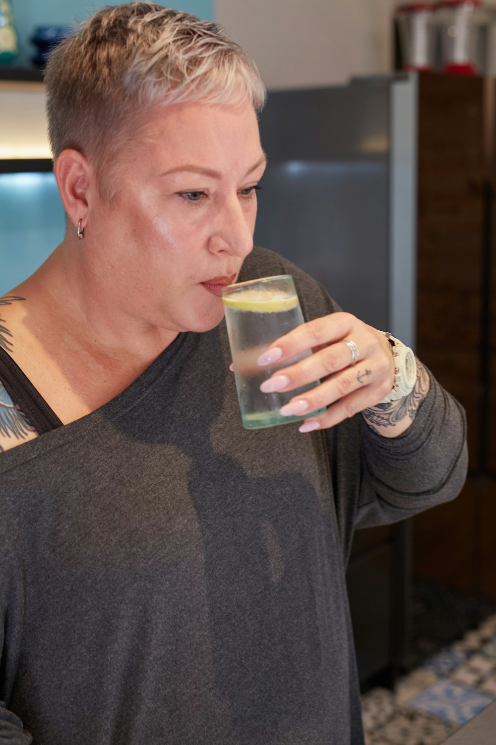 a woman drinking a glass of water in a kitchen