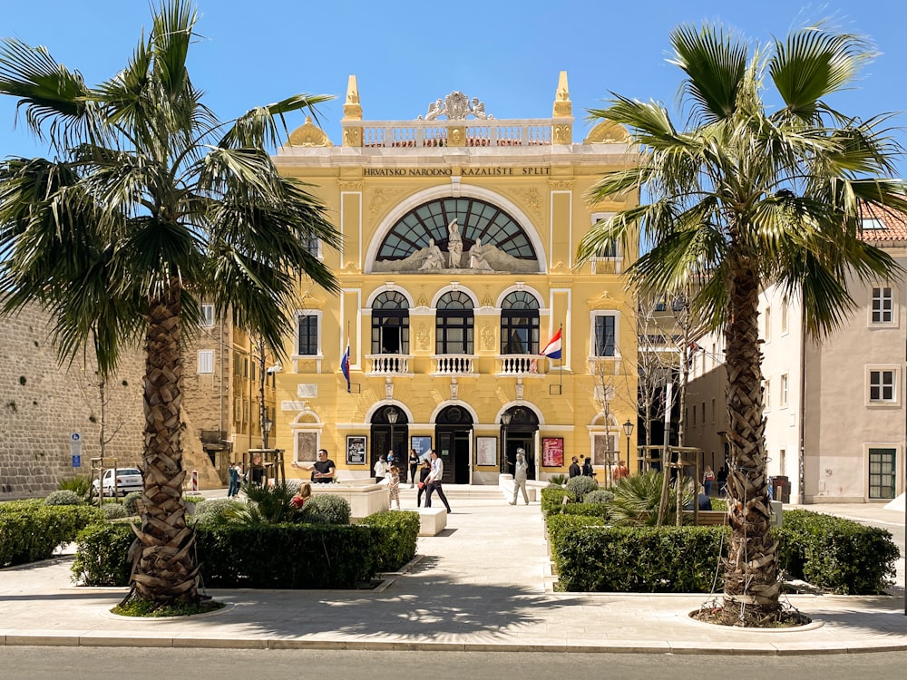 a yellow building with palm trees in front of it