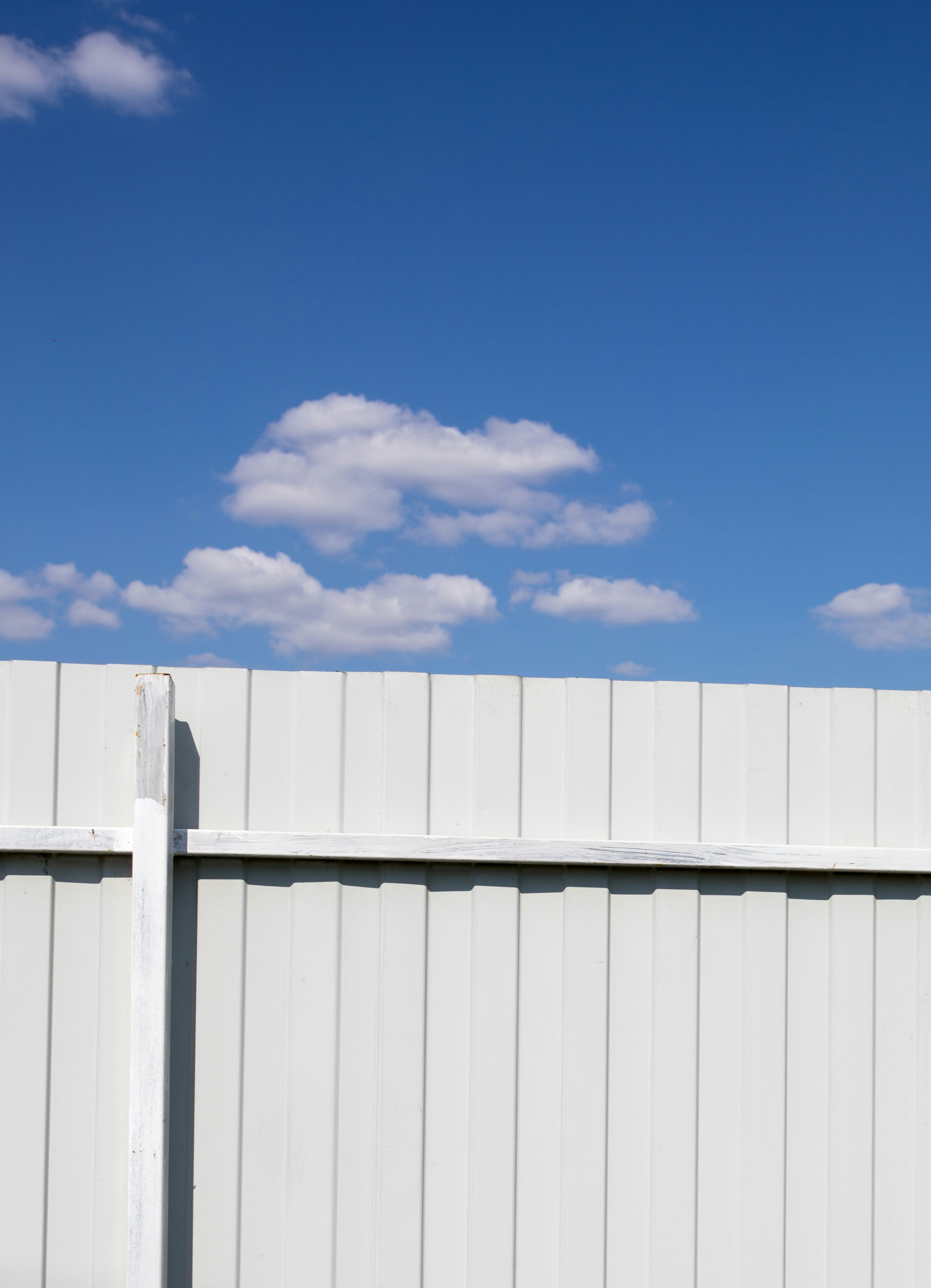 A red fire hydrant sitting next to a white fence photo Free Fence