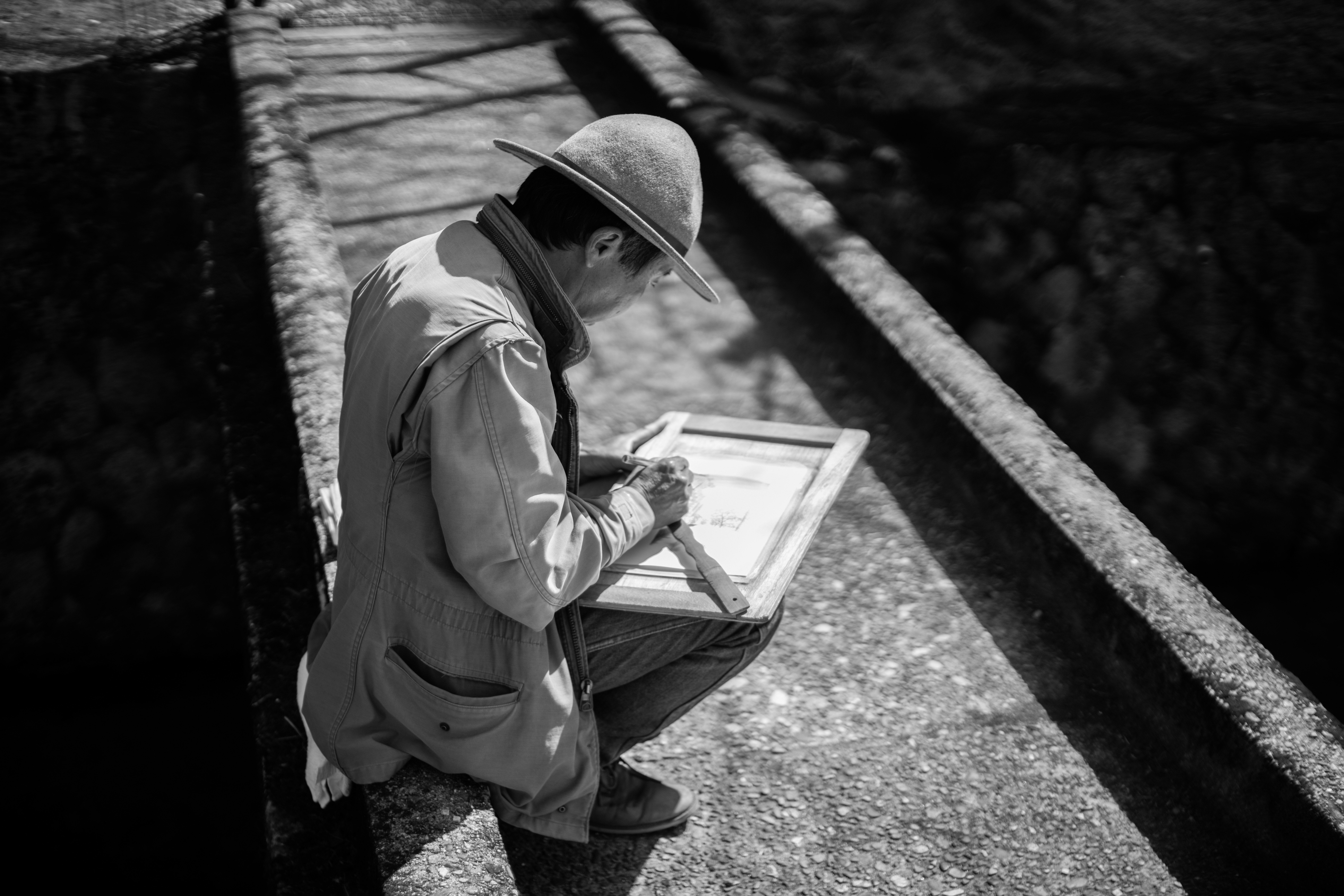 a man sitting on a ledge writing on a piece of paper