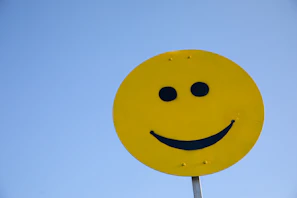 a yellow smiley face sign with a blue sky in the background