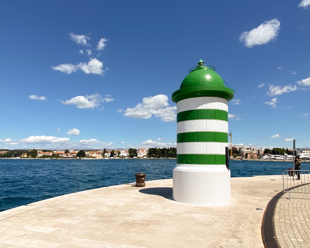 Un grande faro verde e bianco seduto sulla cima di un molo