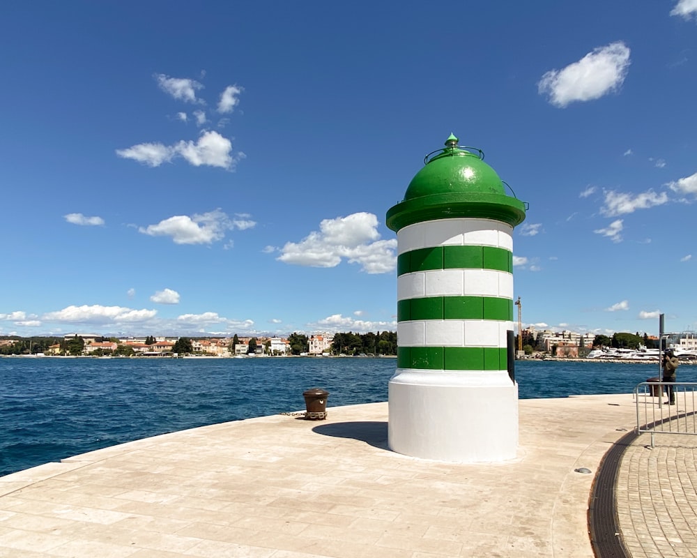 a large green and white lighthouse sitting on top of a pier