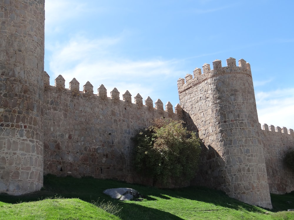 a stone castle with a stone wall and green grass