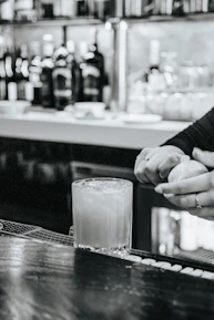 Close-up of a barista mixing a vibrant mocktail with fresh ingredients and tools.
