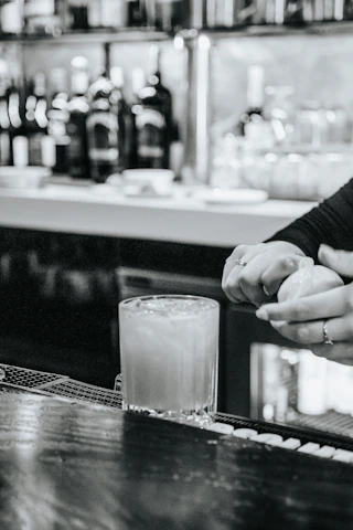 Close-up of a barista mixing a vibrant mocktail with fresh ingredients and tools.