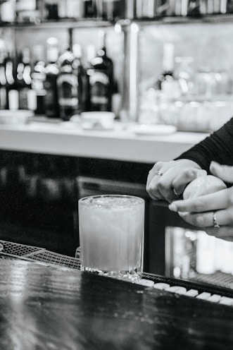 Close-up of a professional bartender's hands skillfully mixing a cocktail at a sleek bar counter.
