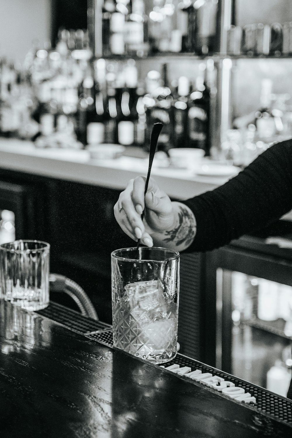 a person holding a spoon in a glass on a bar