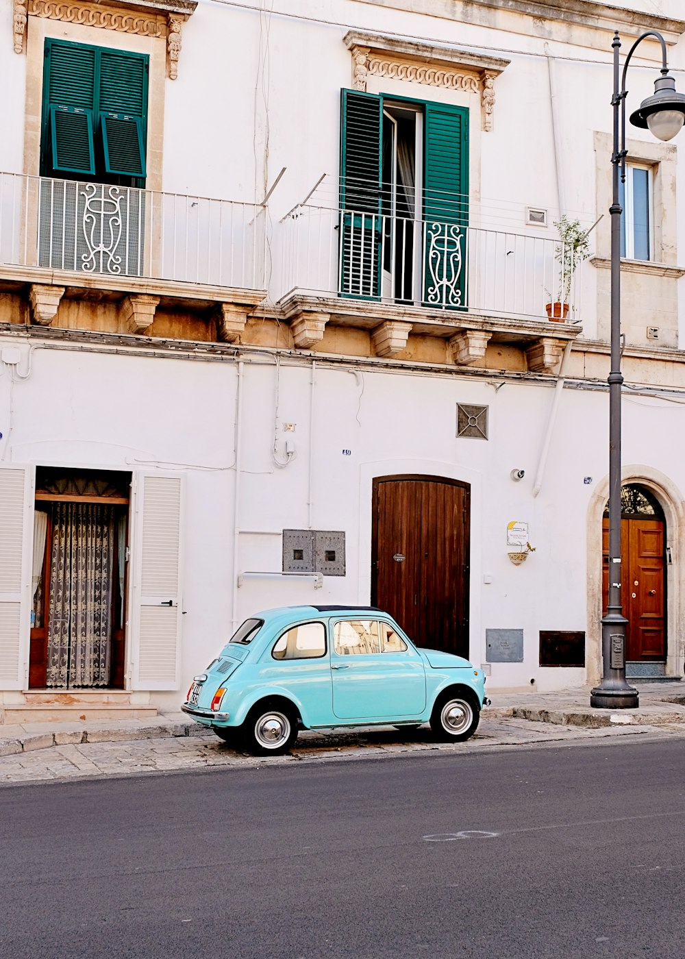 a small blue car parked in front of a building