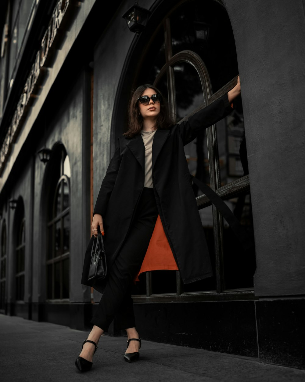 a woman in a black coat is standing outside of a building