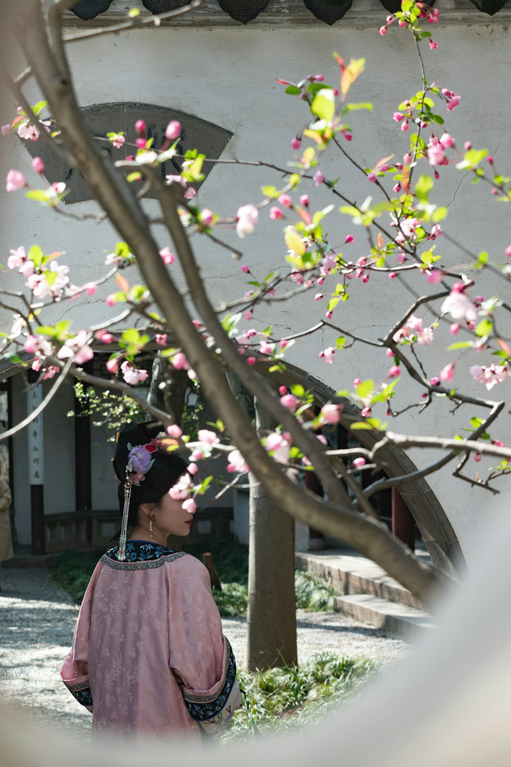 Una donna in piedi sotto un albero con i fiori rosa