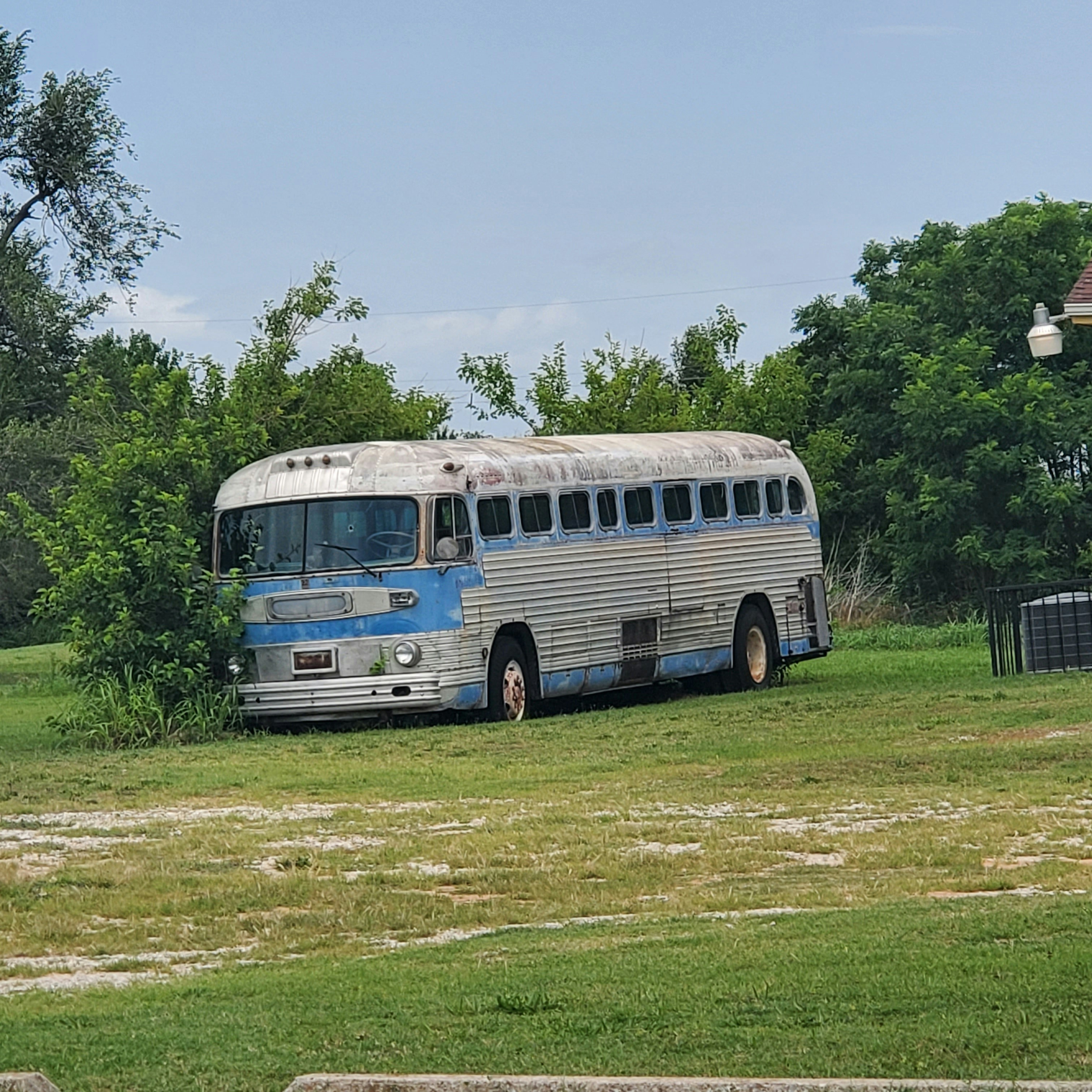 Dark grey charter bus parked at a wedding venue entrance surrounded by manicured gardens, understated and elegant exterior