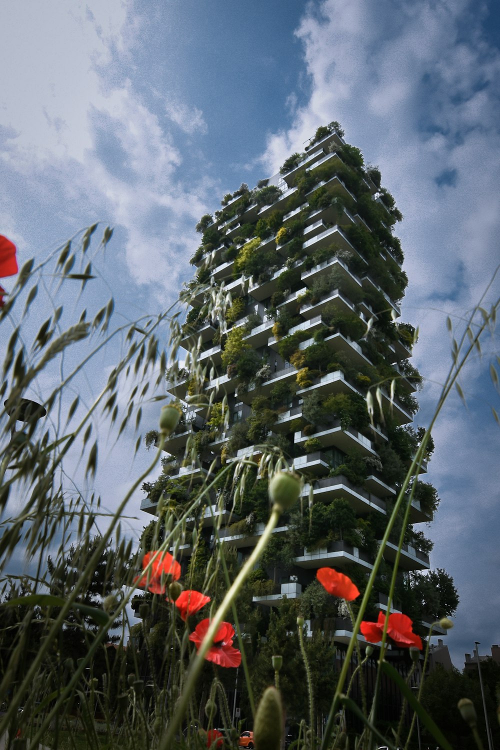 a tall tower with a bunch of red flowers in front of it