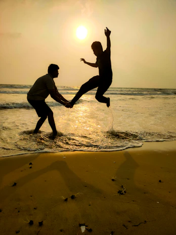 A sunlit candid moment of a couple laughing together on a sandy beach at golden hour.
