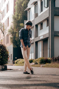 A stylish man wearing a casual outfit standing outdoors with city buildings in the background