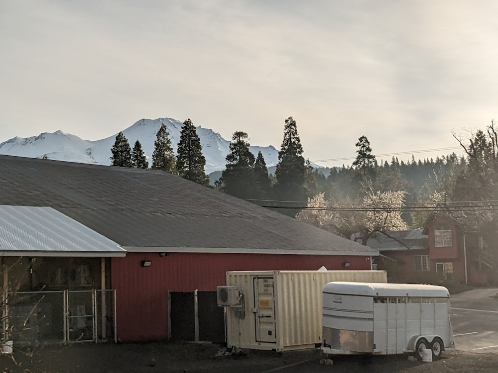 a red barn with a white trailer parked in front of it