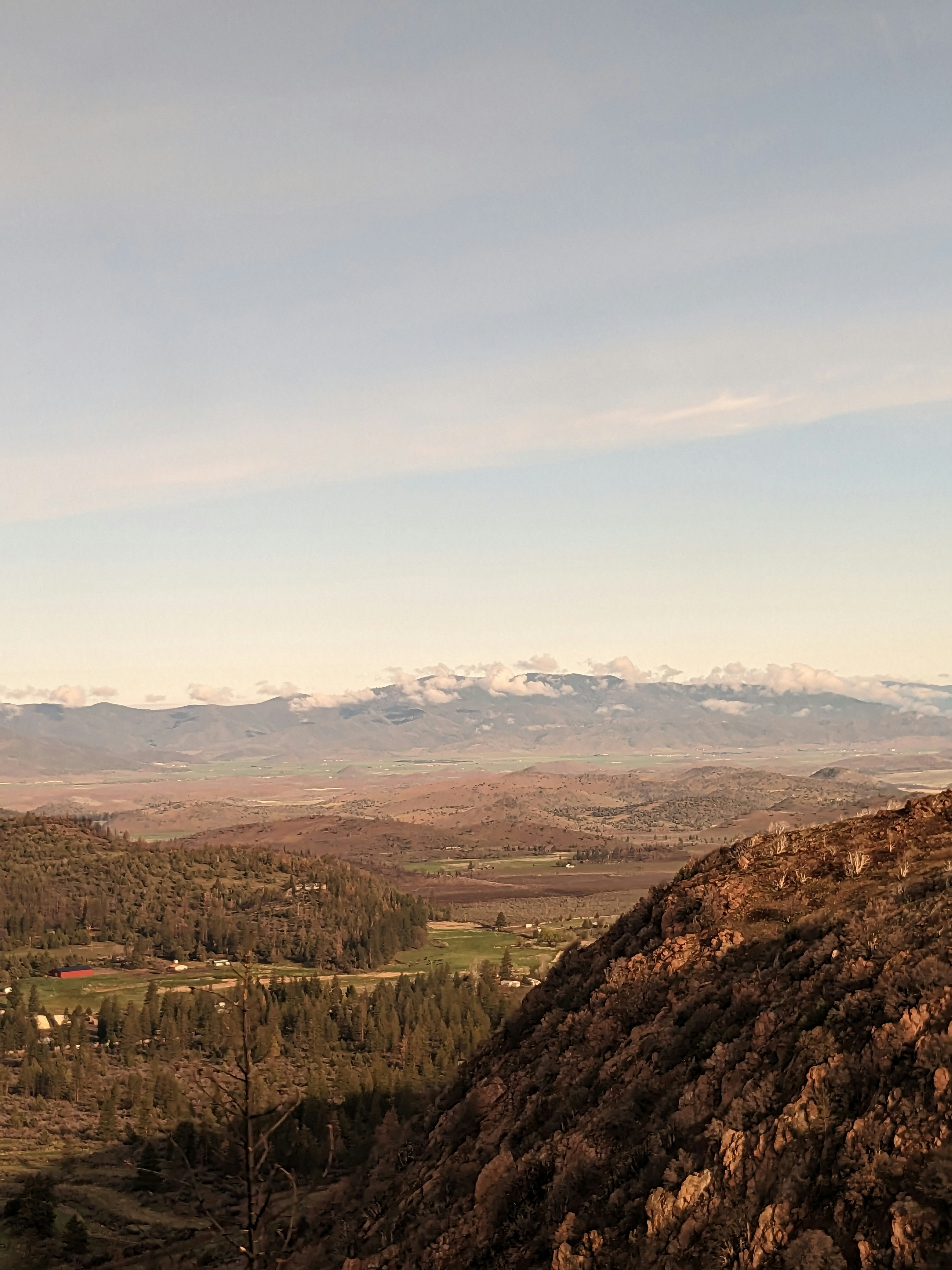 a man sitting on top of a mountain next to a forest