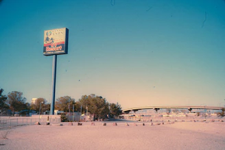A large sign advertising the Oasis Las Vegas RV Resort stands prominently. In the background, there is a highway overpass and a few trees. The landscape appears dry and barren, with a vast open space in the foreground.