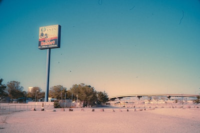 A large sign advertising the Oasis Las Vegas RV Resort stands prominently. In the background, there is a highway overpass and a few trees. The landscape appears dry and barren, with a vast open space in the foreground.