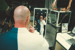 A confident man admiring his fresh haircut in a sleek mirror framed with silver detailing.
