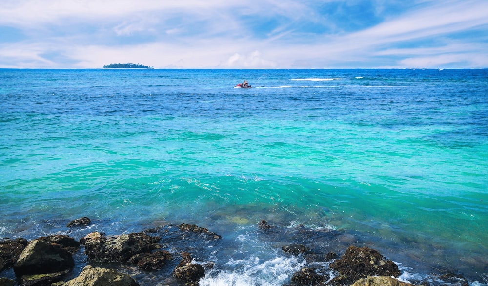 a boat in the ocean near a rocky shore