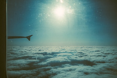 A serene view from an airplane window showing clouds and sun.