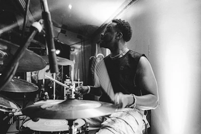 Black-and-white photo capturing a dynamic percussionist mid-performance, sweat and motion blurring into rhythmic energy.