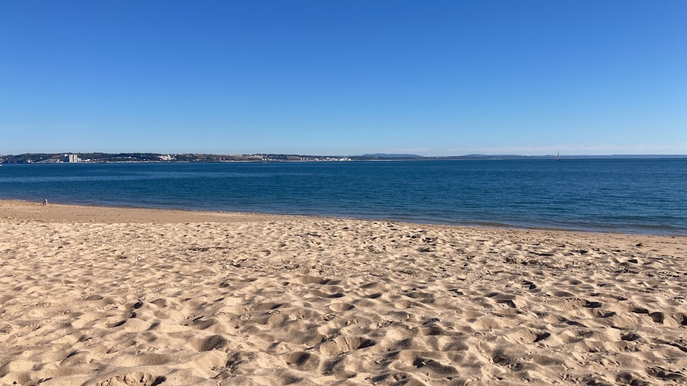 a sandy beach with a body of water in the background