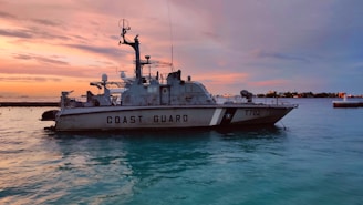 A marine safety officer monitoring coastal waters with binoculars during sunset.