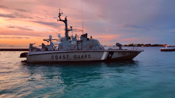 A marine safety officer monitoring coastal waters with binoculars during sunset.