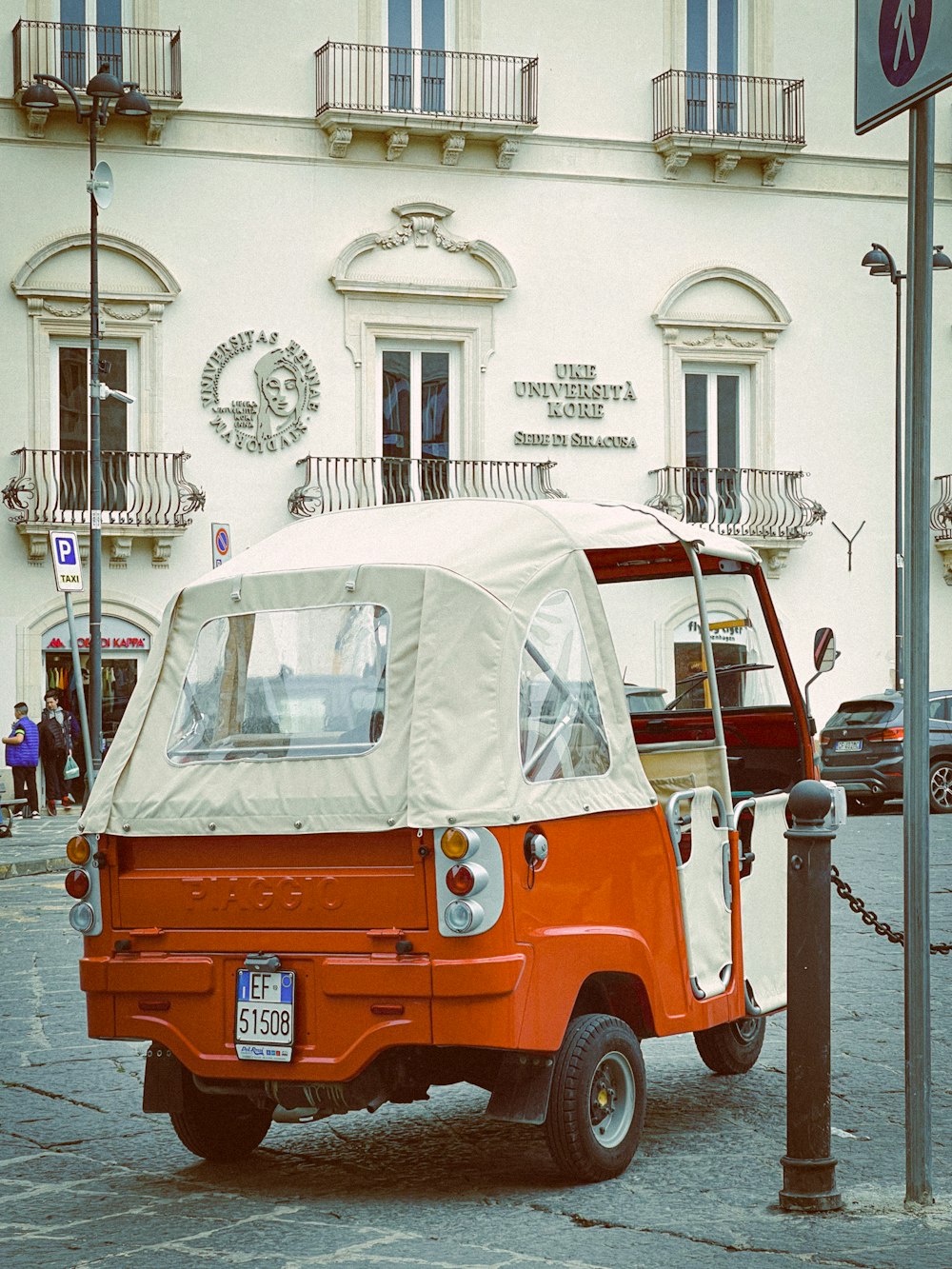 an orange and white small car parked in front of a building