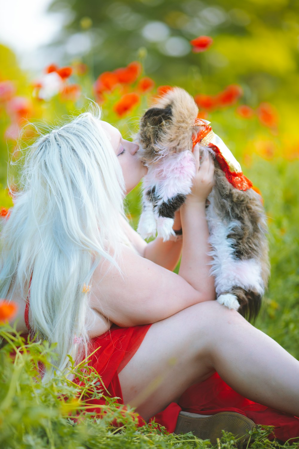 a woman in a red dress is holding a cat